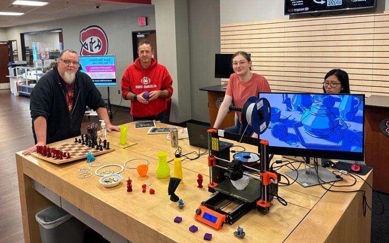 People Near Table of 3D Printer and Items