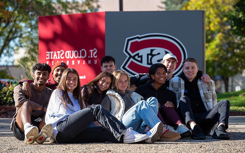 Group of students sitting in front of SCSU sign